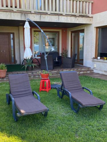 two chairs and an umbrella on the grass in front of a house at A de Bego in Mougás