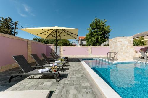 ein Pool mit Stühlen und einem Sonnenschirm neben einem Pool in der Unterkunft Apartman Laura in Vir