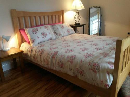 um quarto com uma cama com um edredão branco e rosa em Cosy Beach-side Apartment em Cahersiveen