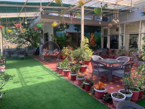 patio ze stołem i mnóstwem doniczek w obiekcie The Panda w mieście Dharamsala