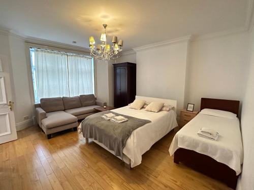 a bedroom with two beds and a couch and a chandelier at En Suite Room & Private Bathroom, in Marylebone, Paddington #room name is paris# in London