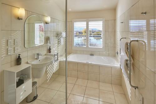 a white bathroom with a tub and a sink at Matuka Lodge in Twizel