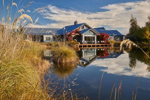 a house is reflected in the water of a lake at Matuka Lodge in Twizel
