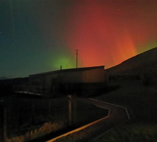 Eine Aurora über einem Gebäude auf einem Feld in der Unterkunft Byre 7 Aird of Sleat in Aird of Sleat