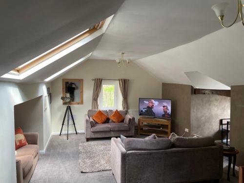sala de estar con 2 sofás y TV de pantalla plana en Danbury Lodge Penthouse, en Matlock