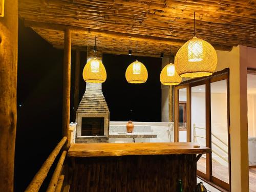a kitchen with three pendant lights and a fireplace at Bali BG Casa Bamboo in Barra Grande