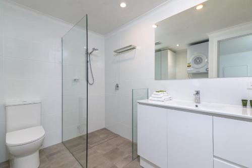 a white bathroom with a toilet and a sink at Seascape Holidays - Coral Apartments in Port Douglas