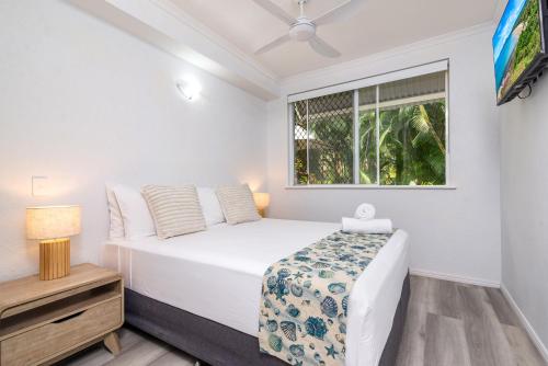 a bedroom with a bed and a window at Seascape Holidays - Coral Apartments in Port Douglas