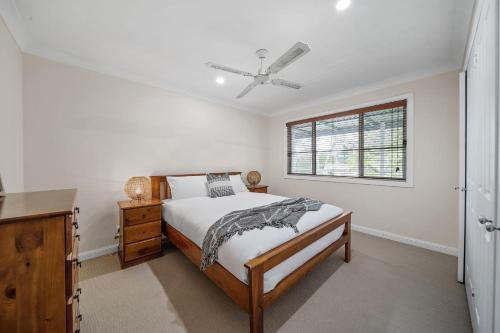 a white bedroom with a bed and a window at Bowen View in Hyams Beach