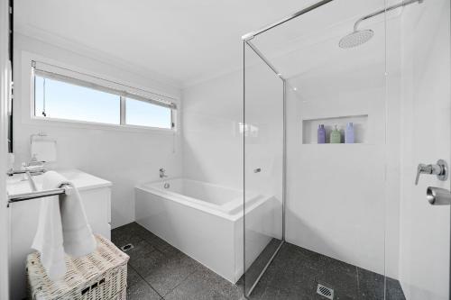 a white bathroom with a tub and a shower at Bowen View in Hyams Beach