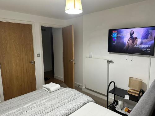 a bedroom with a bed and a flat screen tv on the wall at YES Apartments in Crayford