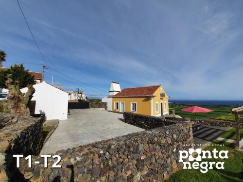 a house with a stone wall next to the ocean at Casa das Lajes in Caldeira