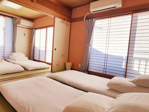 three beds in a room with windows at Hakone Guest House gaku. in Hakone