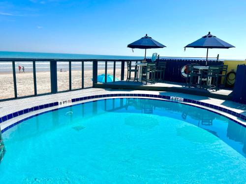 a swimming pool with the beach in the background at Absolute Beach - Sea View at Symphony Beach Club! in Ormond Beach
