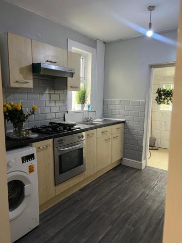 a kitchen with a stove and a washing machine at Spacious family home in Cardiff
