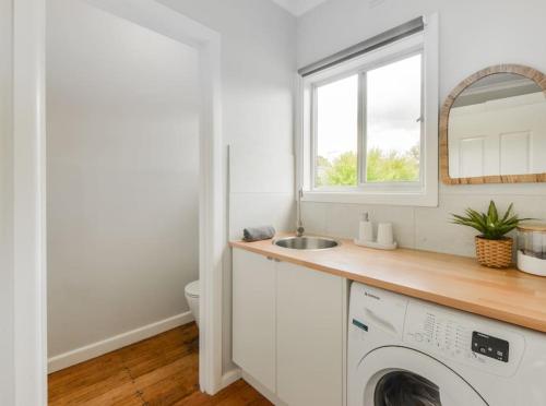 a white kitchen with a sink and a washing machine at Foam St Bliss in Rosebud