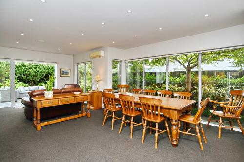 a dining room with a table and chairs and windows at Jeffreys Road - Christchurch Holiday Homes in Christchurch