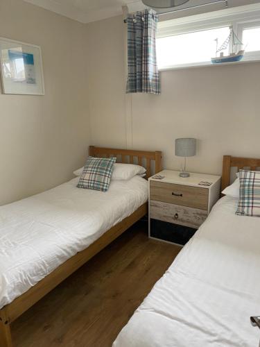 two twin beds in a room with a window at Dunes View - Atlantic Bay in Perranporth