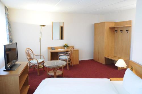 a hotel room with a bed and a table and chairs at AXXON Hotel in Brandenburg an der Havel