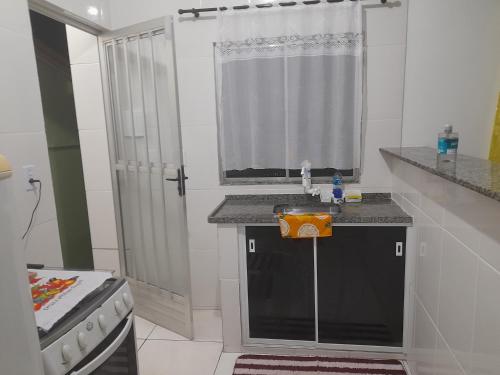 uma pequena cozinha com um lavatório e uma janela em Cantinho da Bethânia em São Pedro da Aldeia