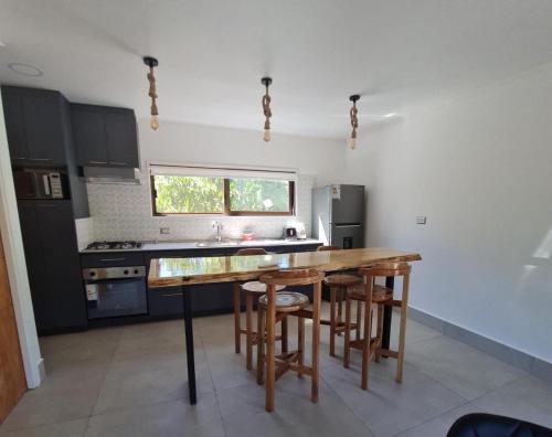 a kitchen with a wooden table and some chairs at Cabañas Pachamama Casablanca in Casablanca