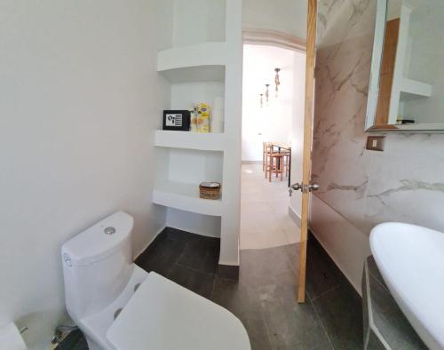 a white bathroom with a toilet and a sink at Cabañas Pachamama Casablanca in Casablanca