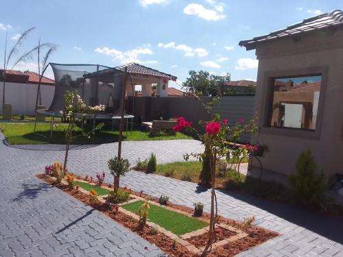 un jardin avec des arbres et des fleurs devant une maison dans l'établissement TLZ Prop B&B, à Pretoria