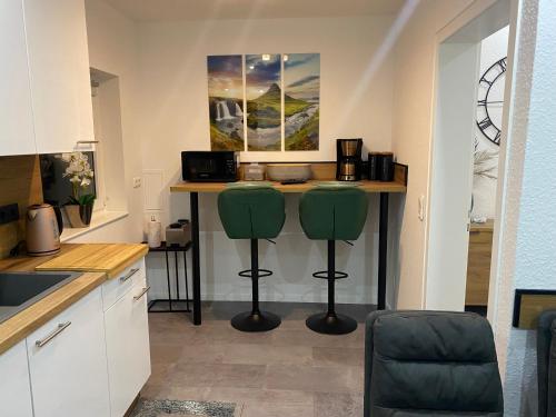 a kitchen with a table and two green stools at Ferienwohnungen Univers A&B in Bad Harzburg