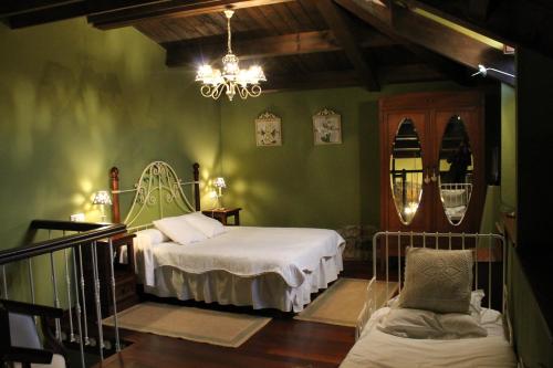 a green room with two beds and a chandelier at Rodiles Rural Apartamentos in Selorio