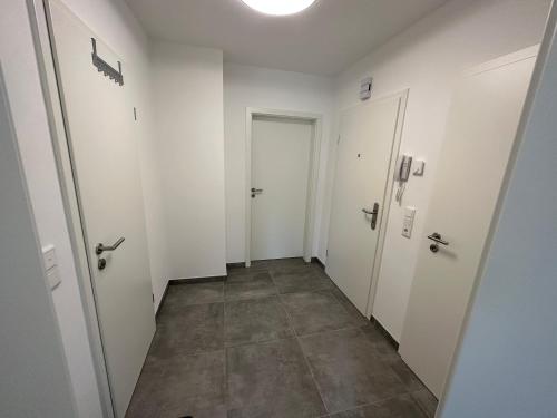 un couloir vide avec des portes blanches et du carrelage dans l'établissement Luxus Apartment, à Oberhausen