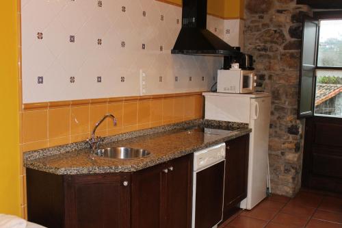 a kitchen with a sink and a refrigerator at Rodiles Rural Apartamentos in Selorio