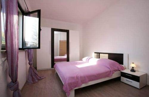 a bedroom with a pink bed and a window at Apartment with pool Adria in Marčana