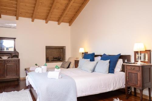 a bedroom with a large white bed with blue pillows at Recanto do Pinheiro in Arga de Baixo