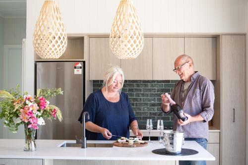 Ein Mann und eine Frau stehen in einer Küche und bereiten Essen vor. in der Unterkunft White Rock Accommodation in Martinborough 