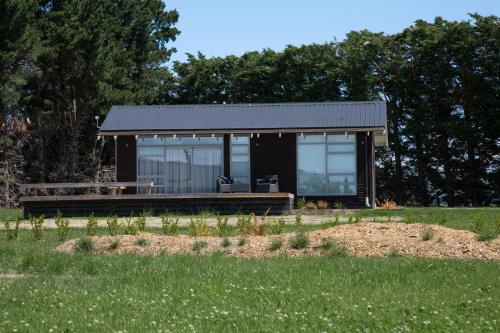 ein kleines Haus mit einer Bank auf einem Feld in der Unterkunft White Rock Accommodation in Martinborough 
