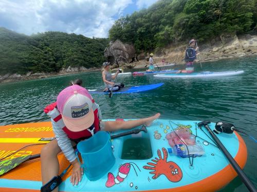 a young girl sitting on a kayak in the water at シーラニ白浜荘 in Kannoura