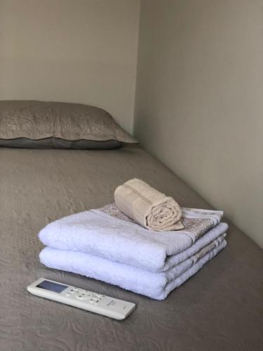 a pile of towels and a remote control on a bed at Aconchego Familiar in João Pessoa