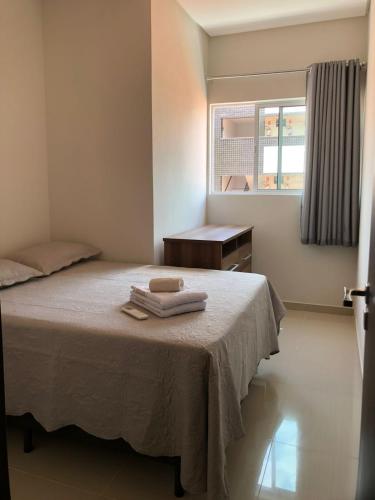 a bedroom with a bed with two towels on it at Aconchego Familiar in João Pessoa