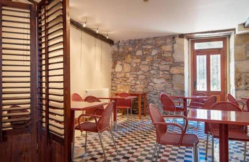 a restaurant with tables and chairs and a stone wall at Hotel Konbenio in Amorebieta-Etxano