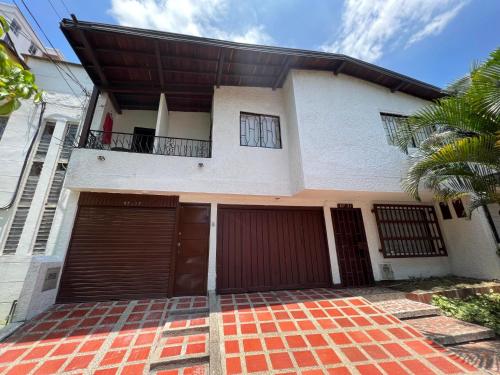 a house with two garage doors and a palm tree at HABITACION AMOBLADA SECTOR LAURELES-ESTADIO #1 Madrid in Medellín