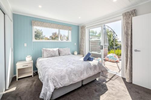 a blue bedroom with a bed and a window at Blue Bungalow in Martinborough 