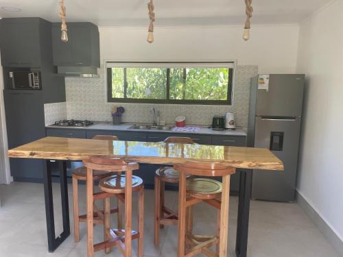 a kitchen with a wooden table and some stools at Cabañas Pachamama Casablanca in Casablanca