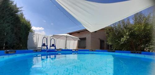 una gran piscina azul con sillas y sombrilla en VIVENCIAS casa rural para 10 personas en Camuñas