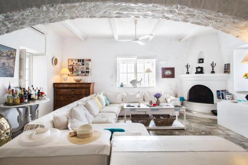 uma sala de estar com mobiliário branco e uma lareira em Lady of Hydra Villa, sea front view, private beach em Hidra