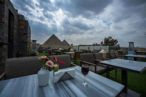 una mesa con una copa de vino en el balcón en Elite Pyramids Boutique Hotel en El Cairo