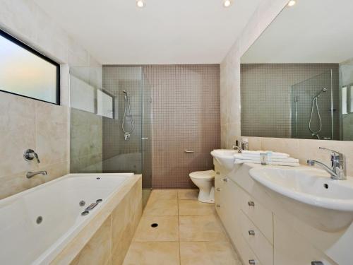 a bathroom with a tub and a sink and a toilet at Moorindil Street in Tewantin