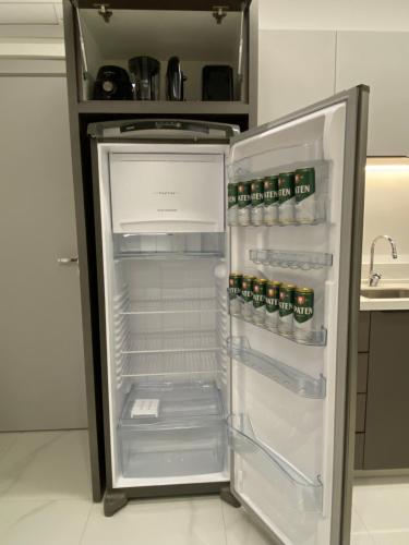 an empty refrigerator with its door open in a kitchen at Loft em prédio com piscina próximo da Oktoberfest Blumenau in Blumenau
