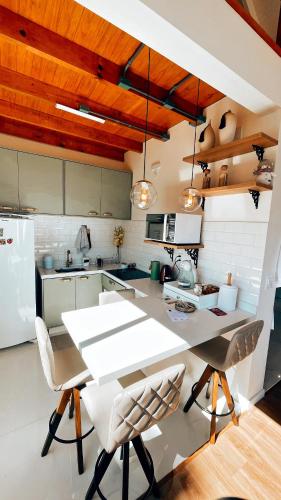 a kitchen with a large white table and chairs at Morada Reino Encantado in São Joaquim