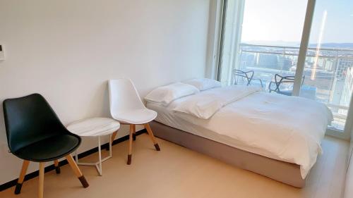 a bedroom with a bed and two chairs and a window at Shine Hotel Incheon Airport in Incheon