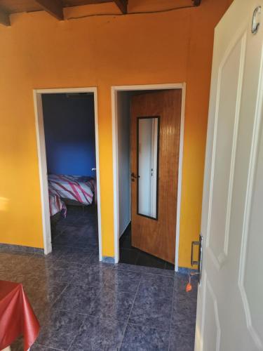 Habitación con paredes de color naranja, puerta y cama en Lindo y cómodo dpto en Garín